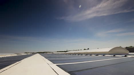 Paneles-Solares-En-Los-Techos-De-Los-Almacenes,-Cielo-Azul,-Plataforma-Rodante-En-Toma