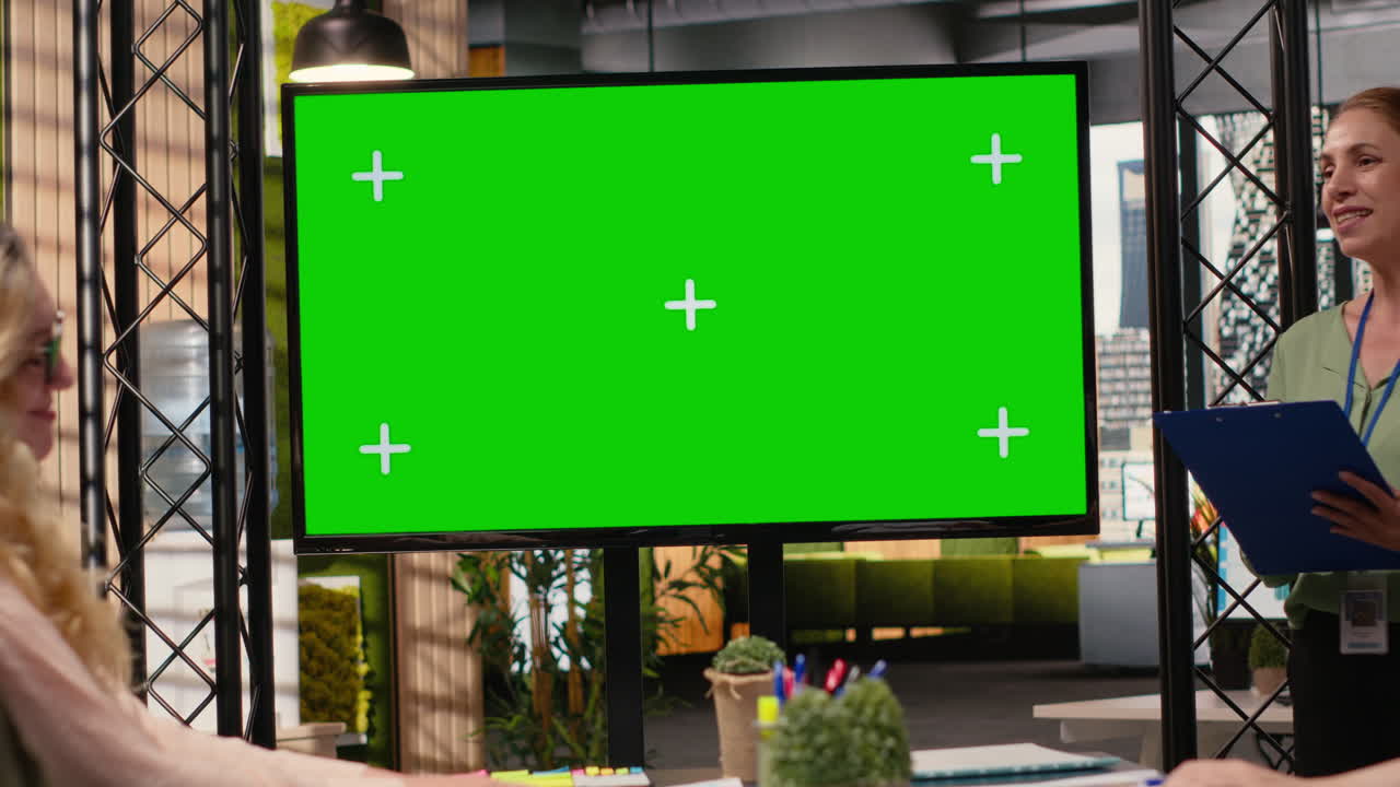 Multiethnic corporate staff gathers in front of a green screen TV display