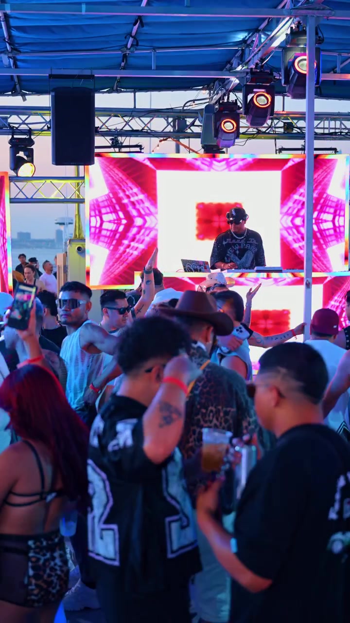 New York, USA, 28 giugno 2026: DJ che si esibisce a una festa in barca LGBTQ con schermo a LED. Il DJ si trova davanti a un display LED rosa sotto le capriate del tendone, circondato da ospiti con in mano dei drink.