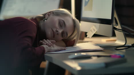 business woman lying on table in office. exhausted woman sleeping near computer