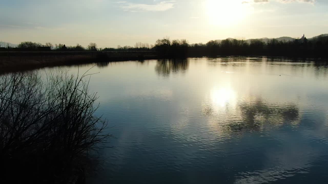 Tree island in the Ribnik Vrbje fishing lake in eastern Slovenia near in silhouette, Aerial dolly in shot