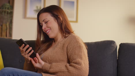 Woman-Sitting-On-Sofa-At-Home-At-Streaming-Or-Watching-Movie-Or-Show-Or-Scrolling-Internet-On-Mobile-Phone-6