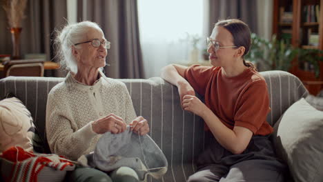 elderly woman knitting and chatting with granddaughter at home