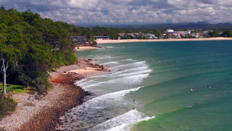 several tourists with surfboards in noosa heads beach in queensland, australia