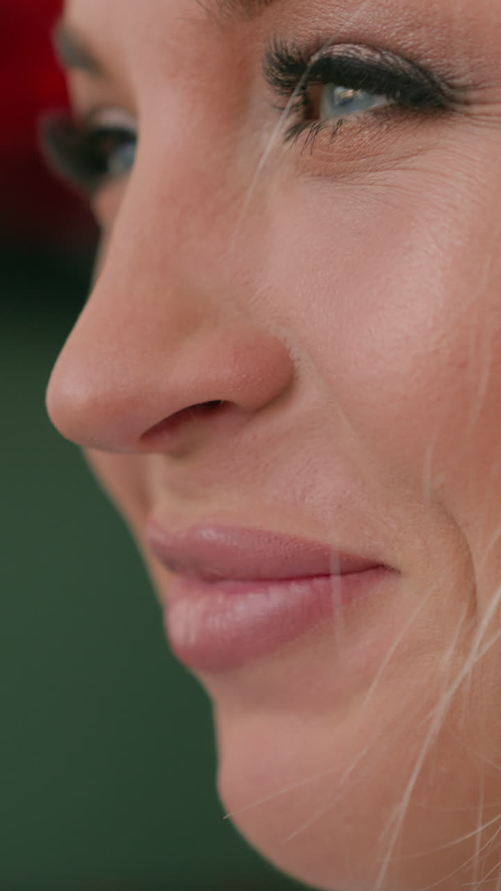 Cheerful blonde woman with glamorous makeup smiles standing on blurred background with blinking lights extreme close side view slow motion