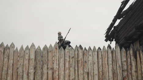 evil knight with spear walks near burnt house behind fence