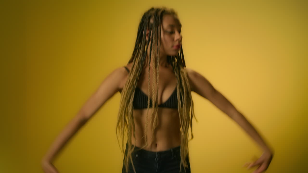 mujer afroamericana bailando en cámara lenta sobre un fondo amarillo