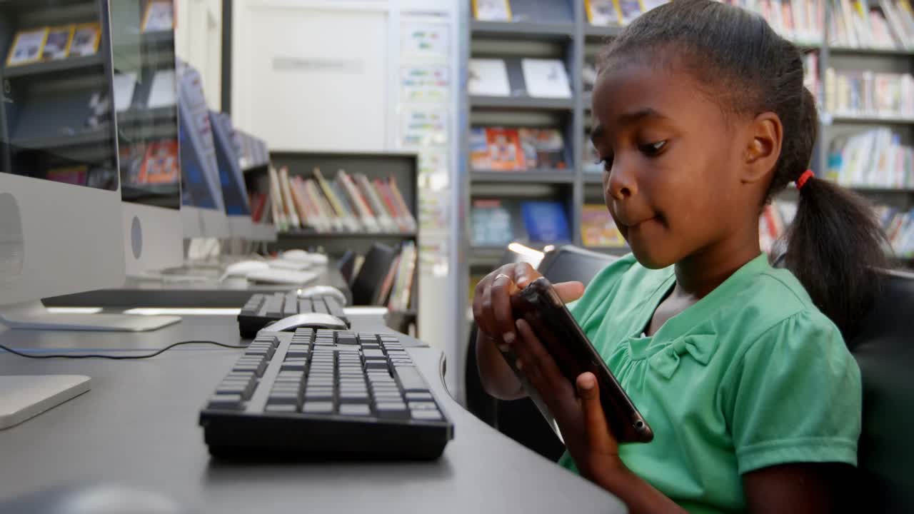 Side view of African American schoolgirl using digital tablet in library at school 4k