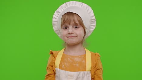 funny child girl kid dressed cook chef baker in apron and hat smiling, fooling around, making faces