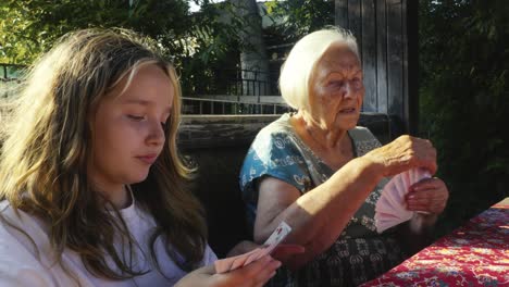 children playing happy family card game with grandma in summer garden