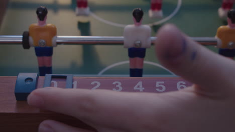 a childs hand moves the scoreboard on a mixture table football game