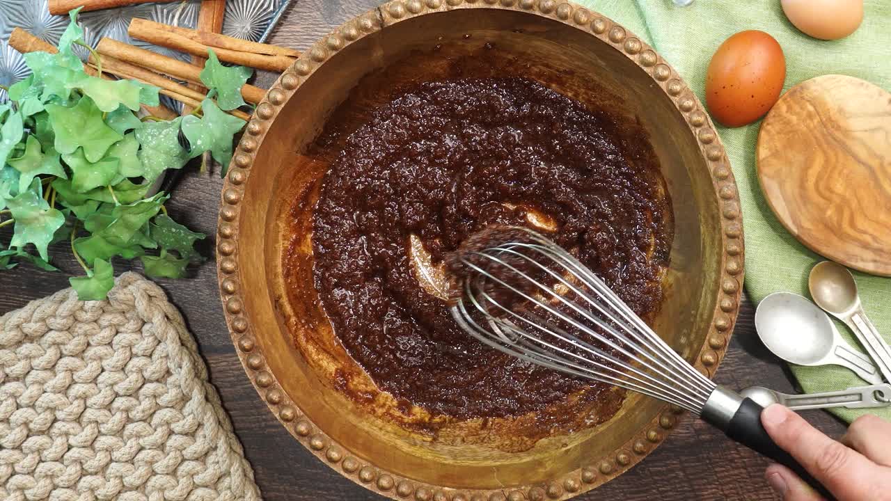 Baking a carrot cake loaf with cream cheese icing and topped with roasted salted pecans. Making a Autumn dessert with carrots, flour, sugar, nuts and frosting. Whisking the ingredients together.