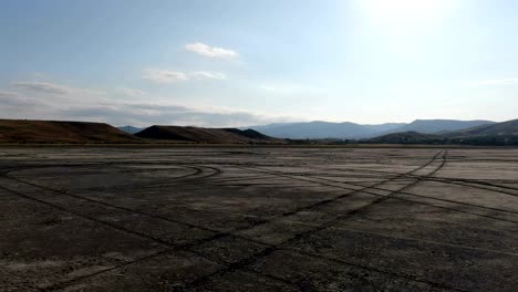 a view from the camera of a drone that circles above the bottom of a dried lake. traces of car wheels remained at the bottom of the lake. mountain ranges are visible on the horizon. crimea august 2019