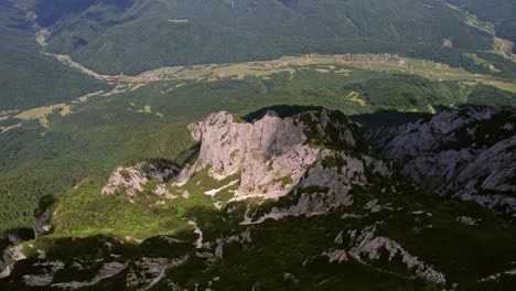 Rugged-cliffs-of-Piatra-Craiului-Mountains-under-clear-skies,-aerial-view