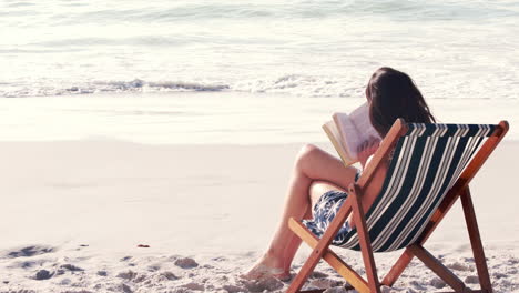 una morena bonita leyendo un libro en una silla de cubierta.