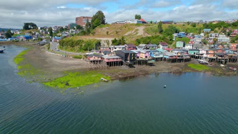 aerial drone orbit of the colorful stilt houses of castro, chiloe on a sunny day.