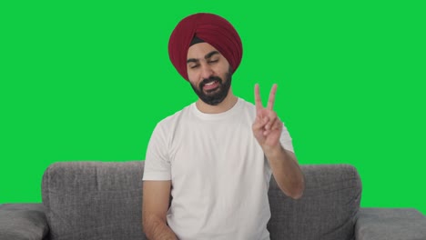 hombre indio sikh feliz mostrando el signo de la victoria pantalla verde