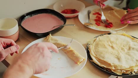 hands layering strawberry sauce on crepes create cozy homemade food moment