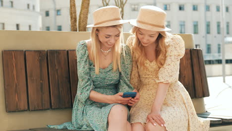 dos amigas sonriendo y usando un teléfono