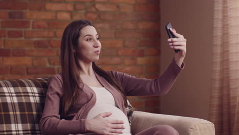 pregnant woman taking a selfie on a couch