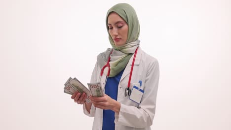 female muslim doctor counting us dollar bills