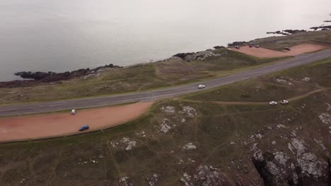 White-car-drives-along-road-at-Punta-Ballena,-Uruguay