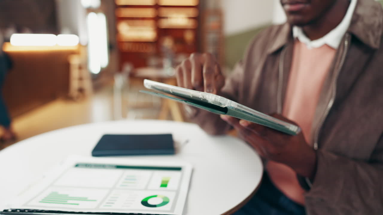 Man working with a tablet and graphs at a desk