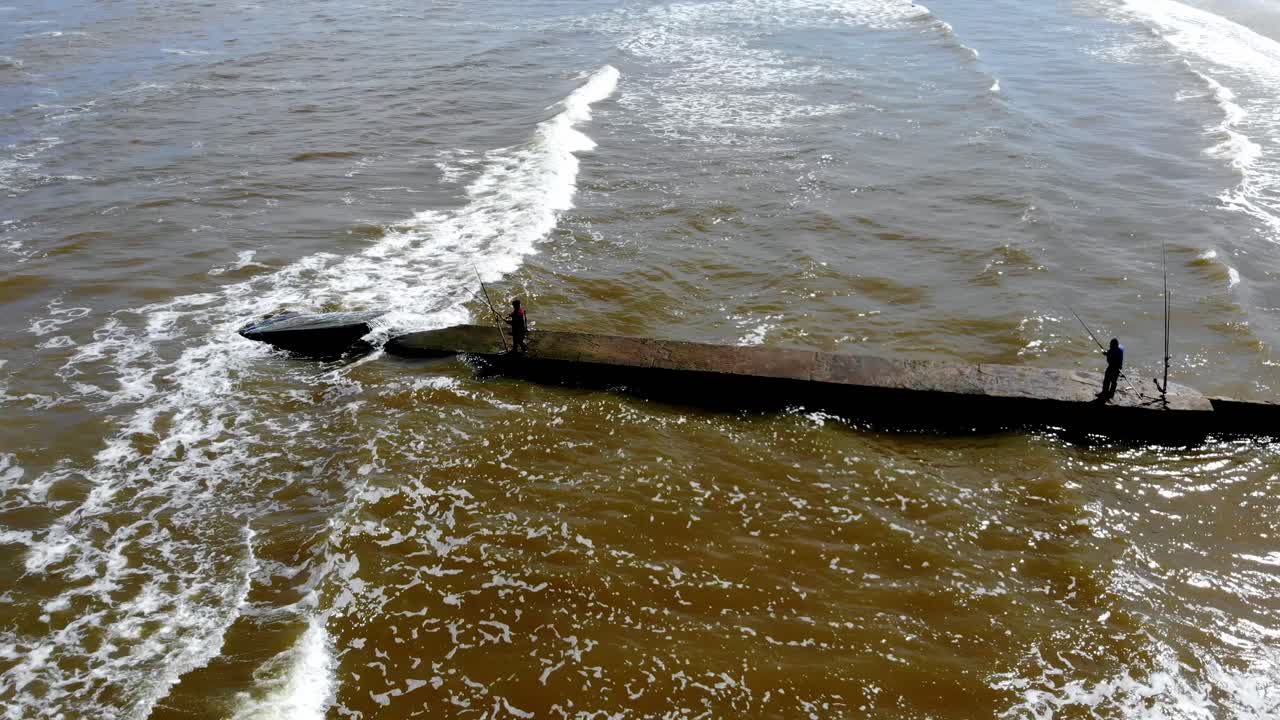 해변에서 낚시하는 두 사람의 항공 영상, 파도가 있는 어느 날