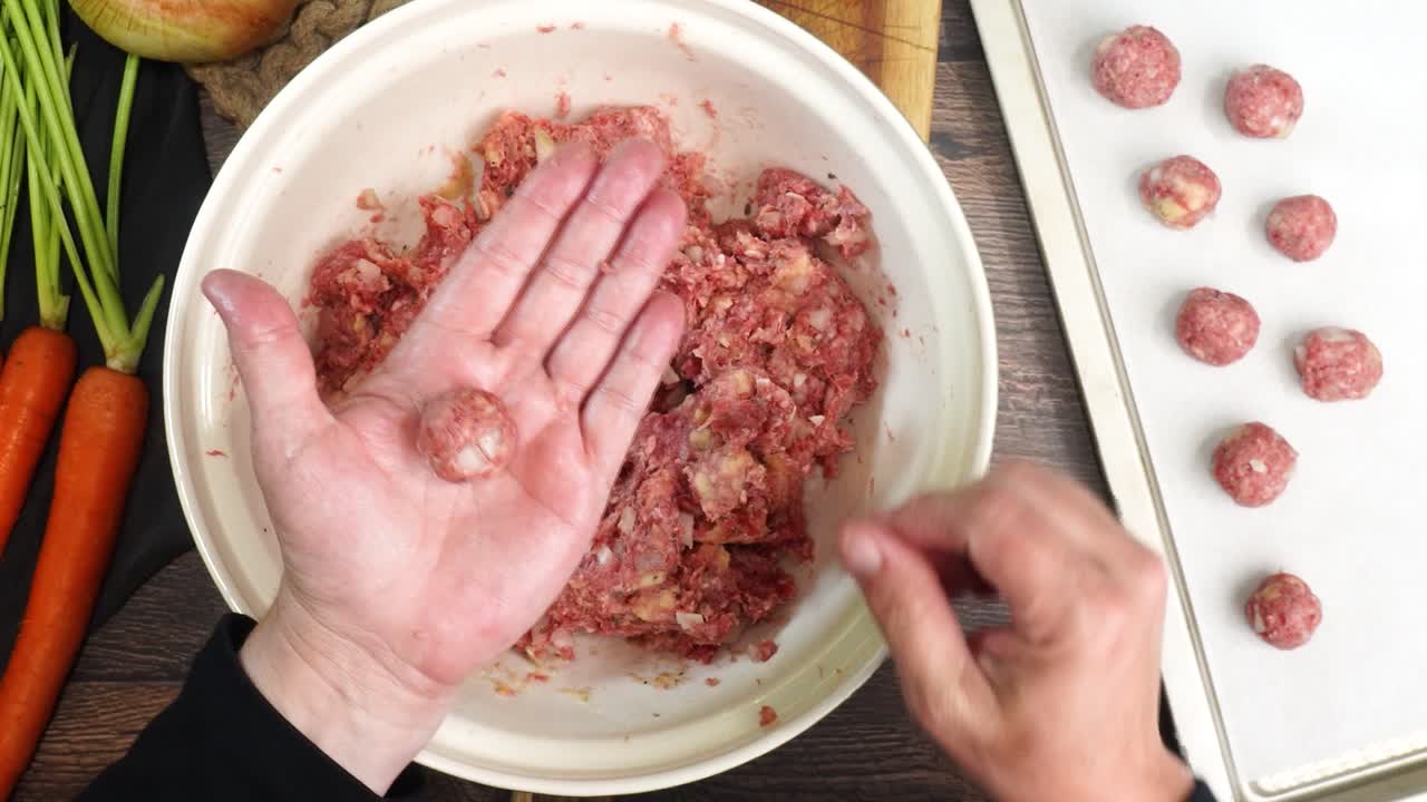 Rolling ground beef meatballs into one each size pieces. Making Italian Wedding Soup and making the meatballs with beef, bread crumbs, onions, herbs, cheese, salt and pepper. Meatball on a baking pan.