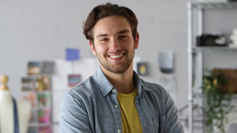 retrato de un estudiante de sexo masculino sonriente o dueño de un negocio que trabaja en la moda por escritorio
