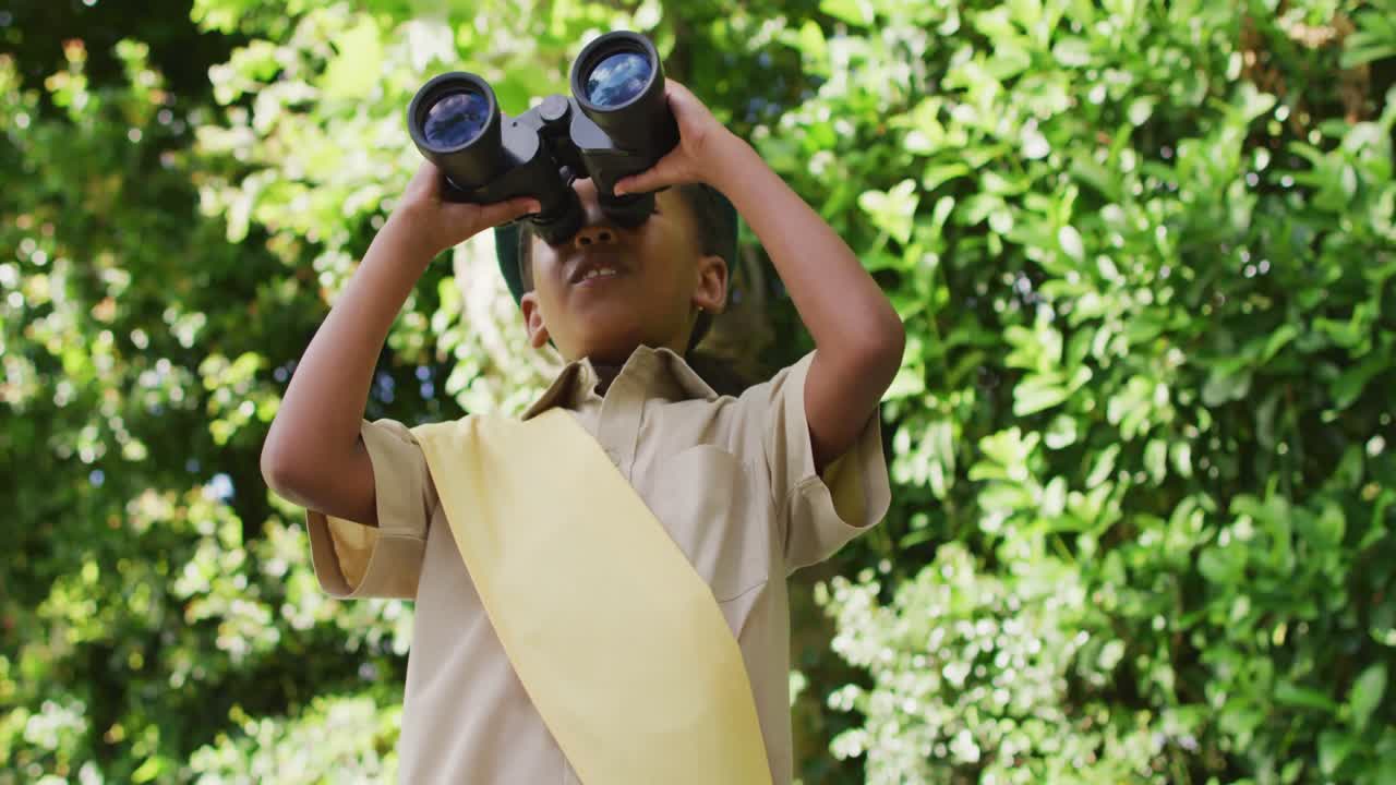 animación de una niña afroamericana en disfraz de explorador usando binoculares en el jardín