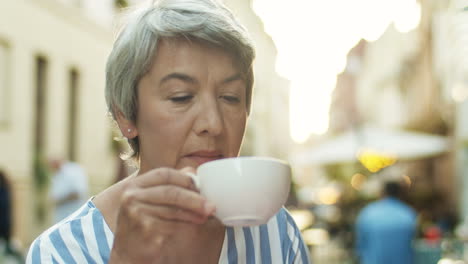 Nahaufnahme-Einer-Ernsten,-Nachdenklichen-Seniorin-Mit-Erschossenen-Grauen-Haaren,-Die-Kaffee-Schlürft-Und-Im-Freien-Denkt