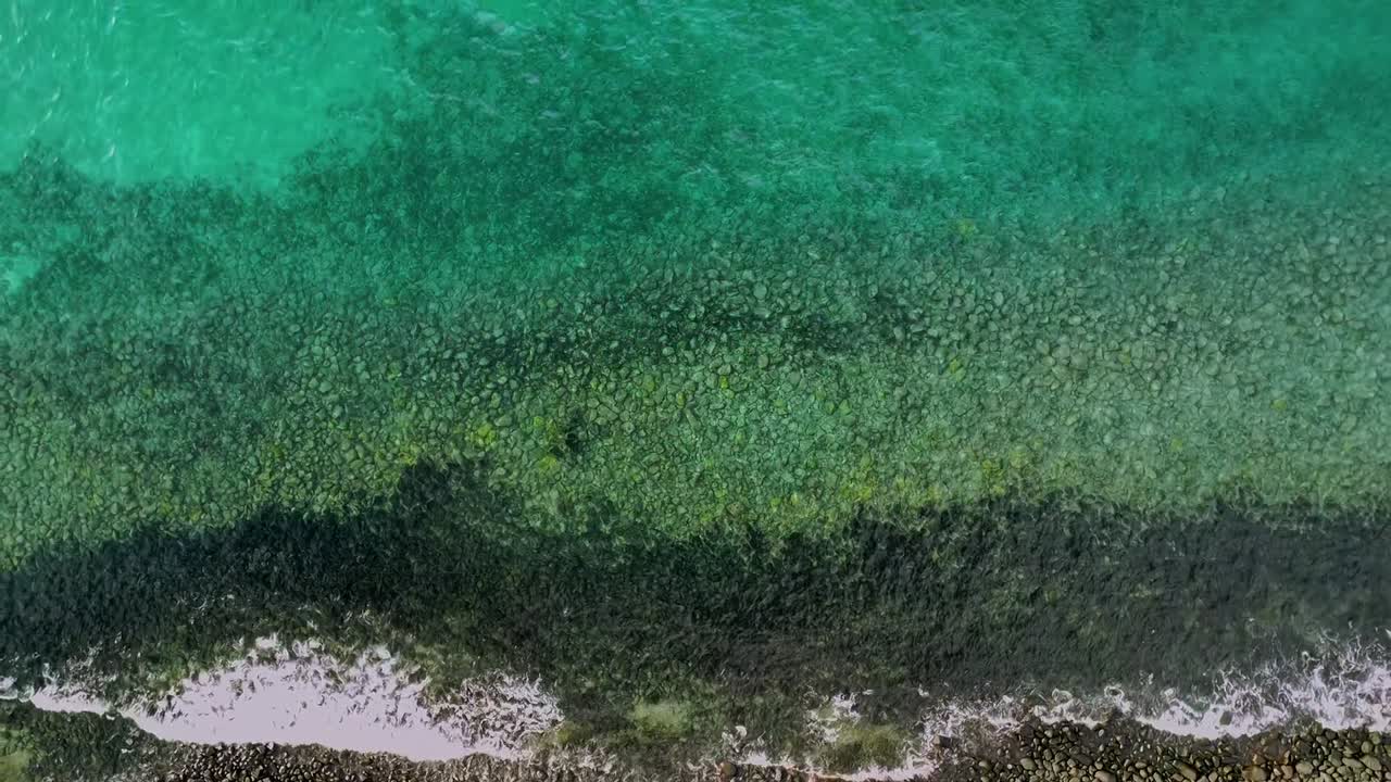 Barriera corallina e fondale roccioso nel Parco Nazionale Marino di Abrolhos, Caravelas Bahia Brasile, con acqua atlantica limpida e turchese e motivi delle onde, ripresa dall'alto con drone in ascesa, rotazione e slow motion.
