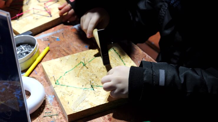 Children, during practical Christmas workshops, hammer nails into shapes and create decorations with yarn