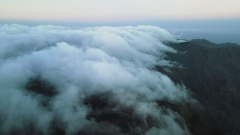 Vista-Fílmica-De-Nubes-Ondulantes-En-La-Cima-Del-Pico-De-La-Montaña,-Anochecer-España