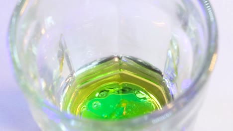 macro shot of green substance falling into golden liquid