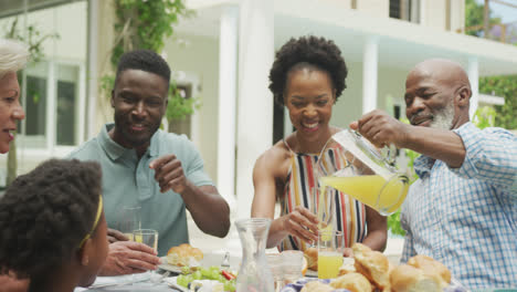 happy african american family drinking juice and having breakfast in garden