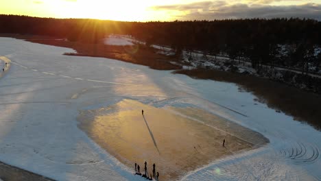 Vista-Aérea-De-Personas-Jugando-Hockey-Sobre-Hielo-En-Un-Lago-Congelado-Al-Atardecer