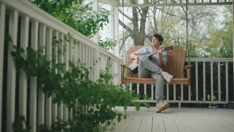 Man Playing Guitar on a Porch Swing