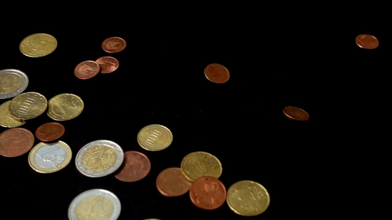 Coins fall on a black background. Slow motion