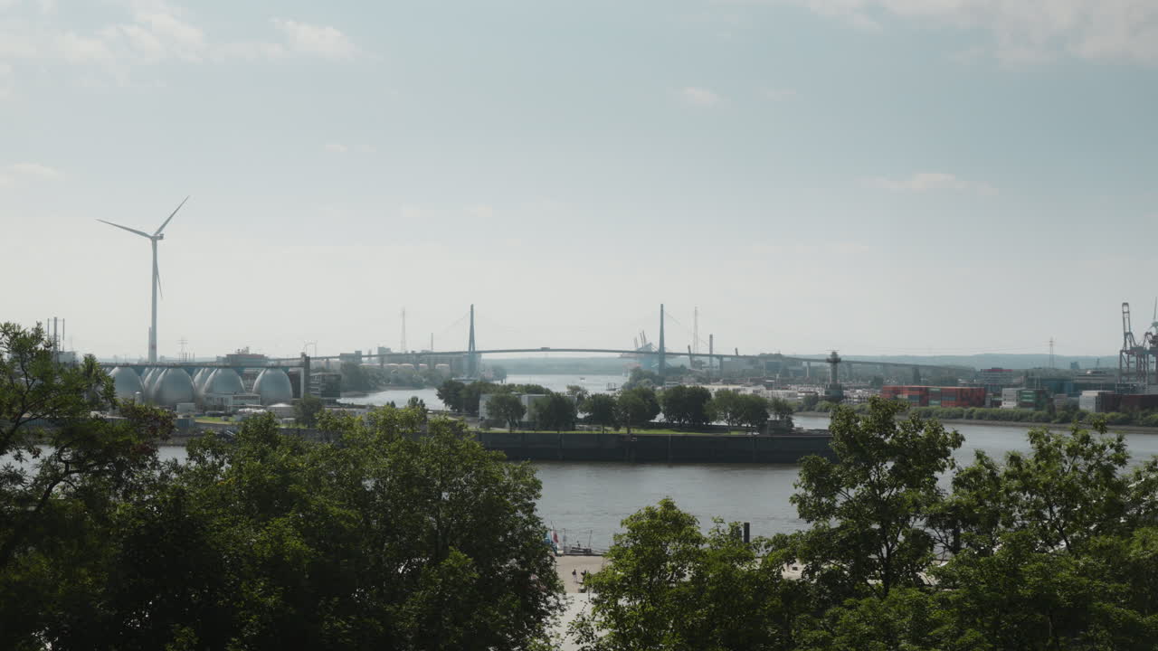 Scenic Hamburg harbor skyline with wind turbine and bridge over serene river elbe from Altonaer Balkon. Perfect for eco-friendly urban development visuals