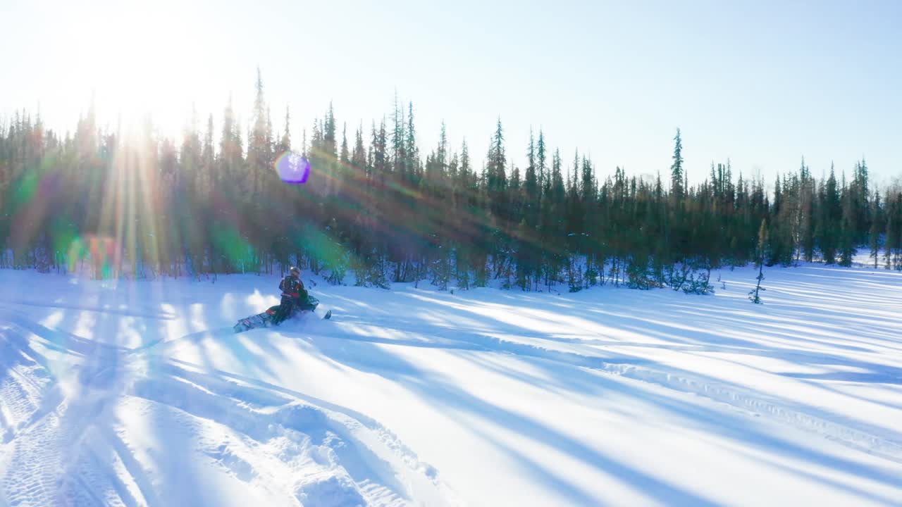 Two friends snowmobiling through the snow-covered terrain of Talkeetna, Alaska, pushing the limits of their snowmobiles, having fun and enjoying the breathtaking winter landscape