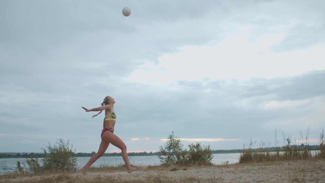 juego de voleibol de playa en el área de recreación deportista está sirviendo entrenamiento de pelota en la cancha de arena disparo en cámara lenta