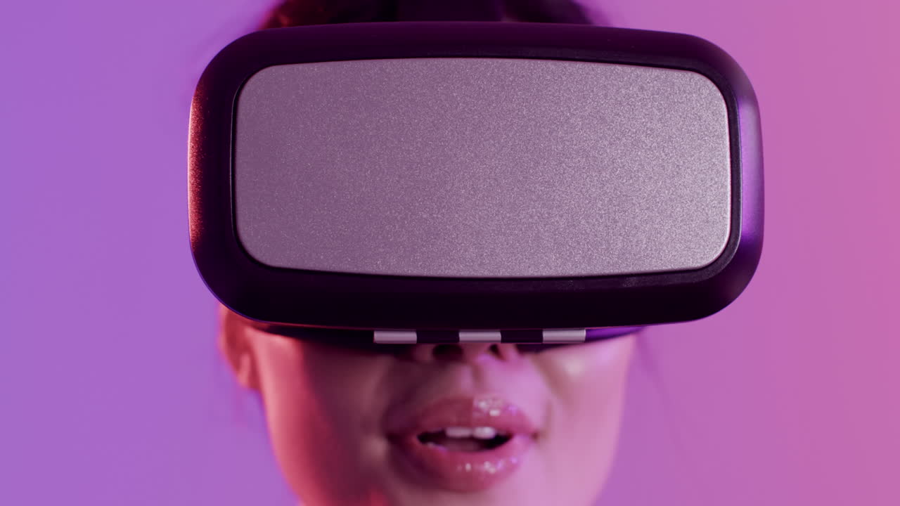 primer plano de una mujer asiática feliz usando auriculares vr sobre un fondo púrpura, cámara lenta