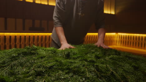 person arranging fir branches in a sauna