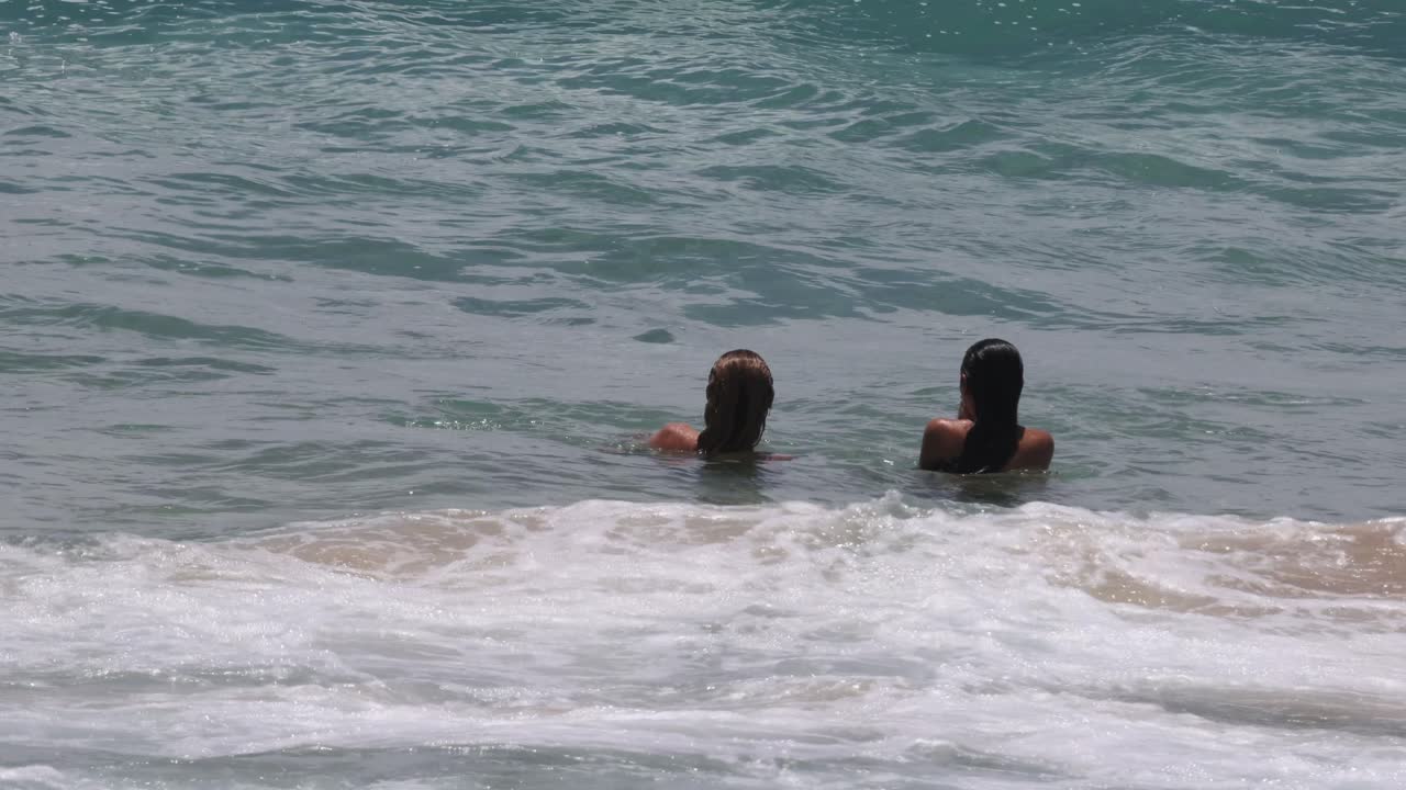 친구 들 의 그룹 이 바다 파도 에서 놀고 수영 하고 있다