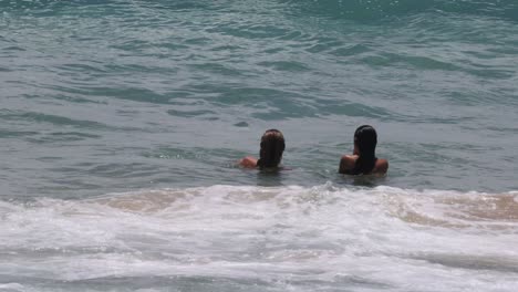 group of friends playing and swimming in ocean waves