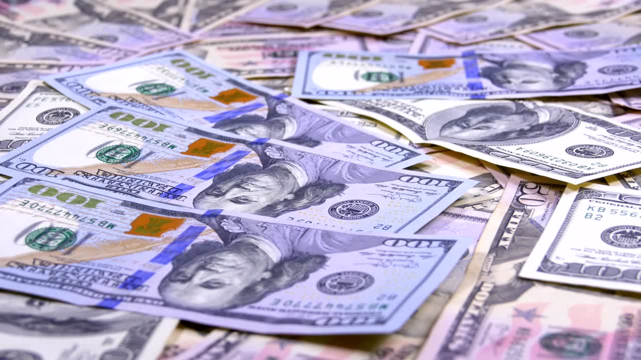 billetes de cien dólares caen sobre la mesa con dólares estadounidenses de diferentes denominaciones