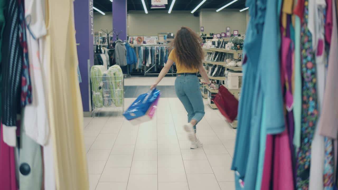 mujer sonriente está girando con bolsas en la tienda de ropa