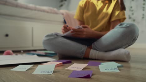 Unrecognizable-caucasian-teenage-girl-sitting-on-floor-and-making-notes-on-flash-cards